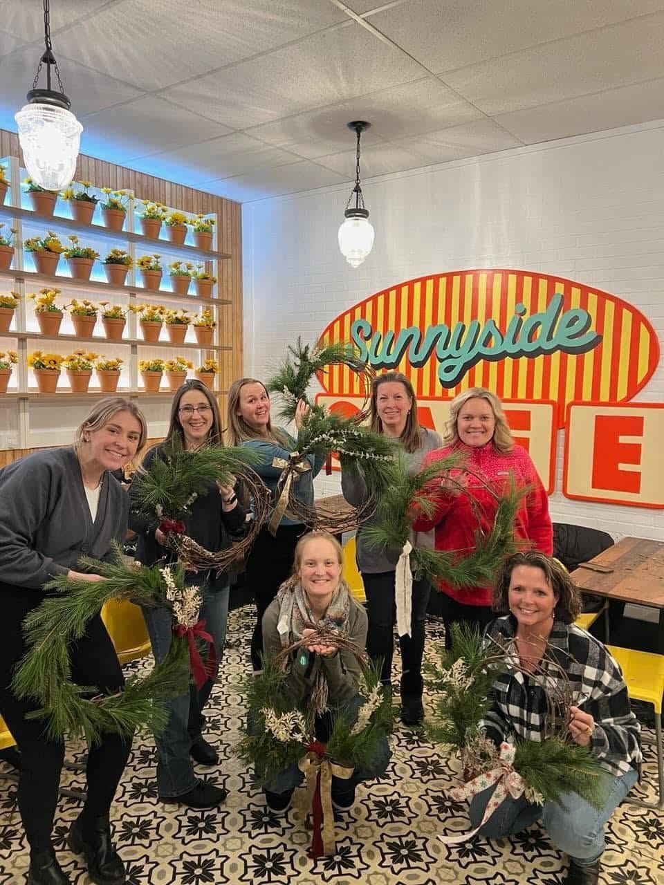 Workshop guests holding their finished wreaths at Sunnyside Cafe
