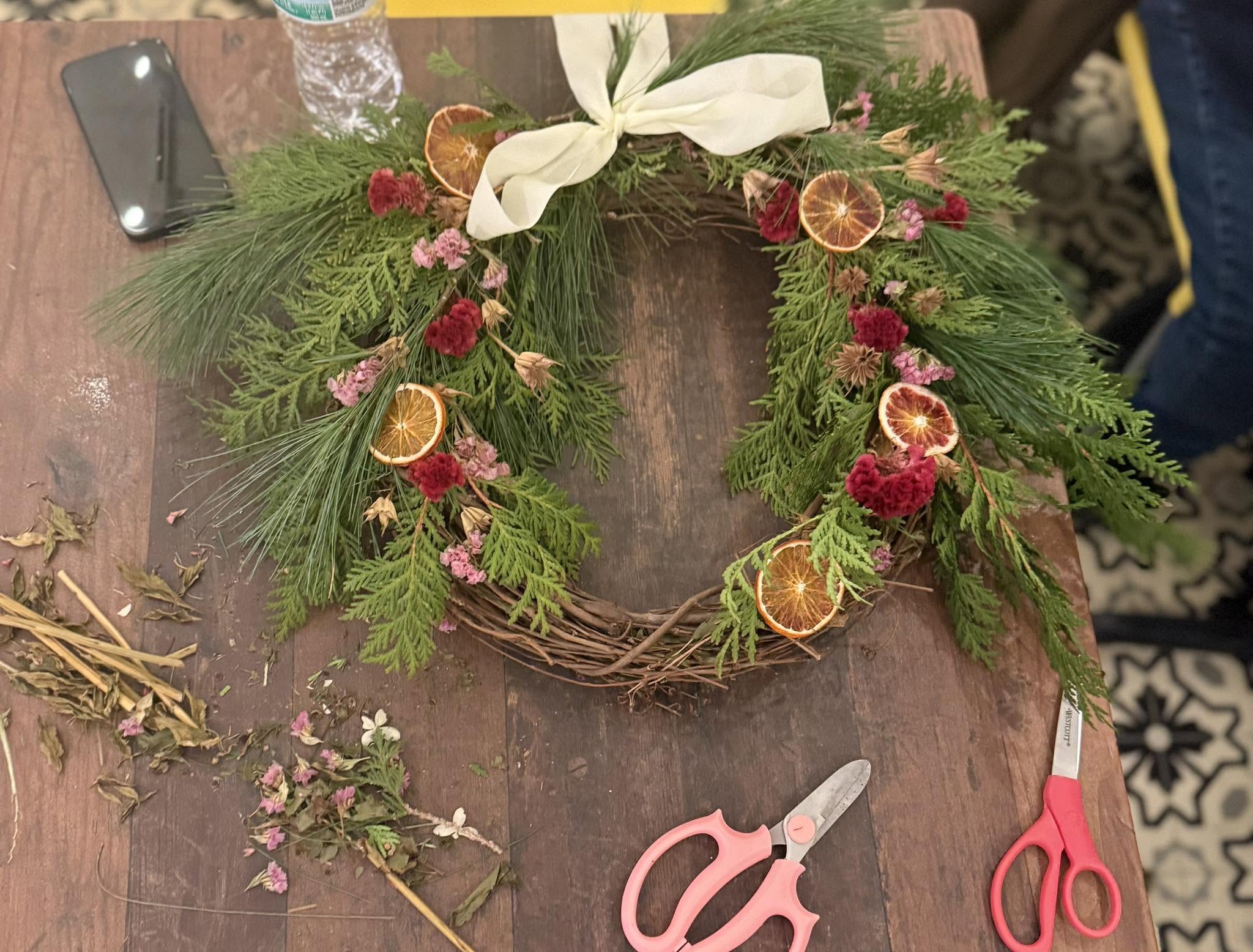 A handmade evergreen wreath with dried oranges and ribbon at a Sunnyside workshop